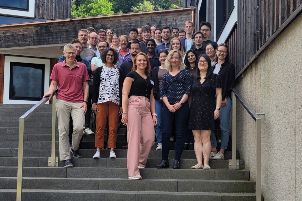 A group picture of the participants of the 3rd SyMoCADS retreat on the stairs in front of a Forschungscampus Waischenfeld